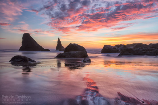 Getting low to the ground, I was able to see reflections on the beach in Bandon, Oregon during a dramatic sunset. 