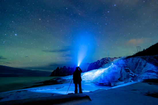 Landscape Photographer with headlamp in front of starry sky in winter by Ugo Cei